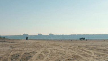 Motorcu kumlu plaj boyunca sürme. Motosikletçi üzerinden çöl Motosiklet sürmek.