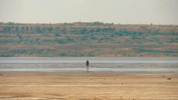 L'uomo stanco attraversa il deserto fino all'acqua e guarda giù — Video Stock