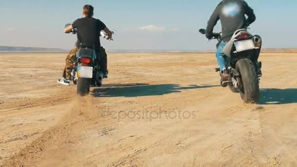 Motociclistas a lo largo de la playa de arena. Los ciclistas viajan en motocicleta por el desierto . — Vídeos de Stock