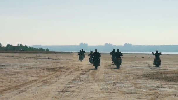Många motorcyklister Ridning längs sandstranden långt borta. Bikers dra kolumn. — Stockvideo