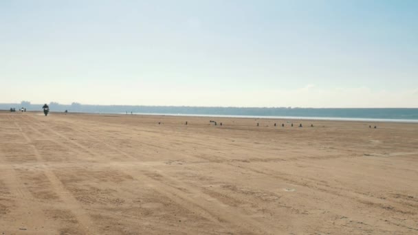 Muchos motociclistas viajan a lo largo de la playa de arena desde muy lejos. Columna de ciclistas . — Vídeos de Stock