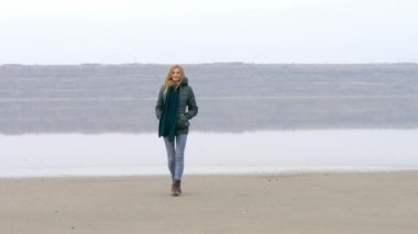 Kameraya kumsalda yürüyüş ve sis sis içinde gülümseyen genç güzel kız.