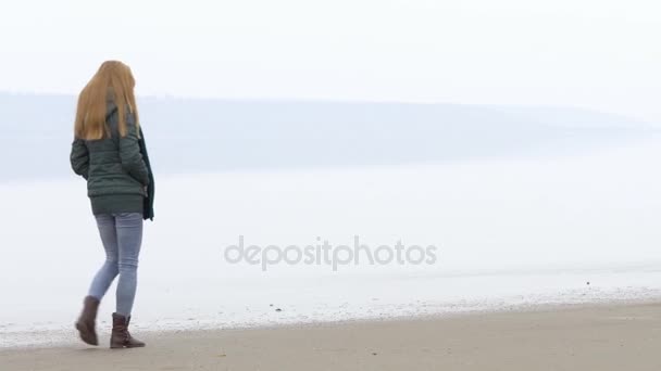 Menina bonita jovem que vai embora na praia de areia da esquerda para a direita. Fechar — Vídeo de Stock