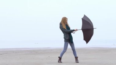 Sisli puslu Plajda şemsiye rüzgara karşı çekerek pretty genç kız