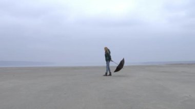 Pretty genç kız sağdan sola puslu Sahilde yürüyüş şemsiye çekerek