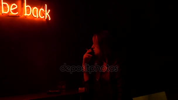 Sad girl lights and smokes a cigarette in night club — Stock Video