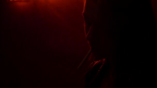 Девушка закуривает сигарету спичками в ночном клубе — стоковое видео
