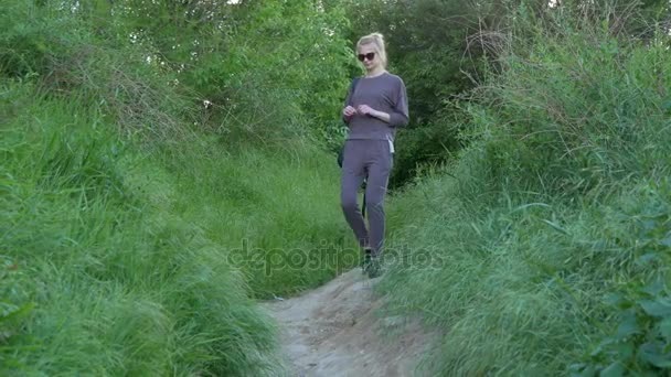 Szép, fiatal lány leszáll egy utat a hegy tele zöld fű — Stock videók