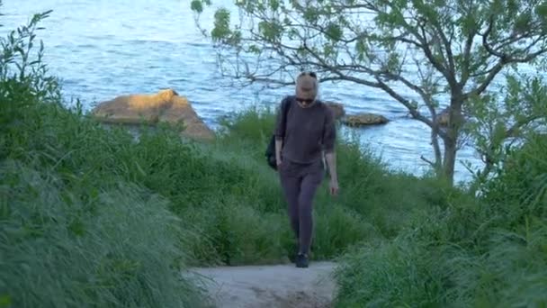 Belle jeune fille grimpe un chemin sur une colline près de la mer — Video