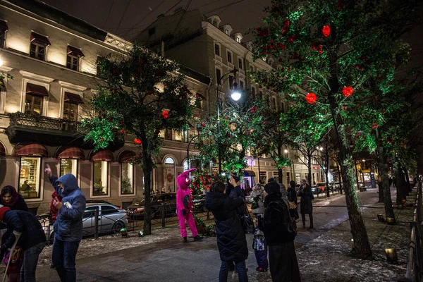 street in the park with people on the background of trees decorated with roses late in the evening