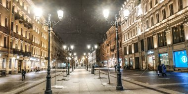 Gece yarısı kar yağarken fenerlerin arasında yaya caddesi