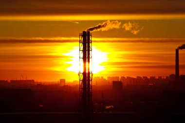 Günbatımı arka planında fabrika uzun boru