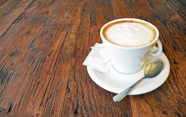 Šálek cappuccino na pozadí dřevěný stůl — Stock fotografie