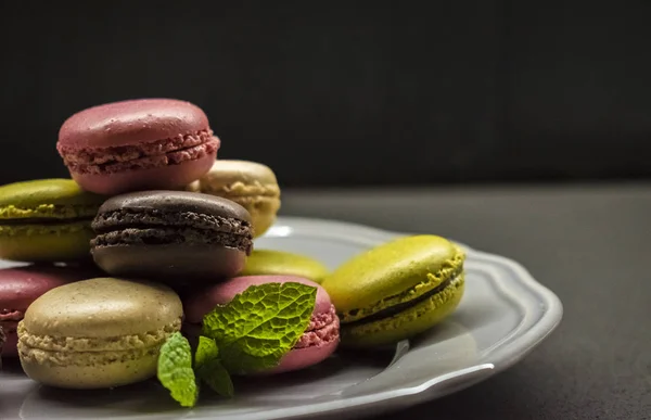 Цветные печенье макарон на тарелке, темный фон — стоковое фото