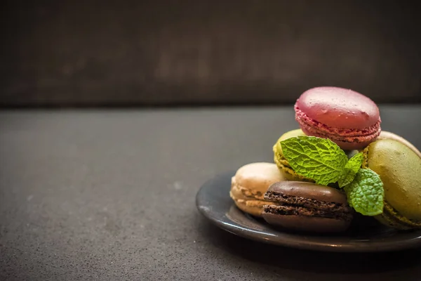 Цветные печенье макарон на тарелке, темный фон — стоковое фото