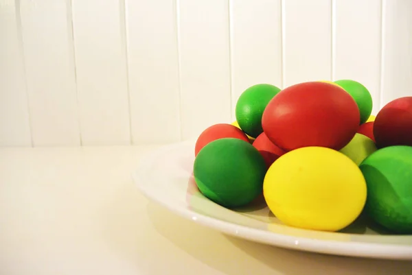 Цветные красно-зеленые и желтые пасхальные яйца на тарелке . — стоковое фото