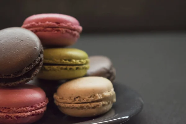 Galletas de macarrones de color en la placa, fondo oscuro — Foto de Stock