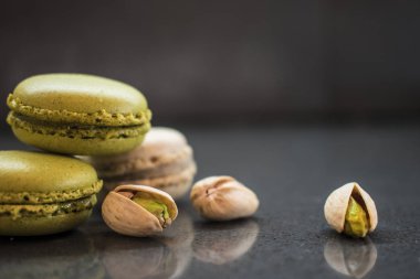 iki fıstık macarons koyu arka plan üzerinde fındık ile