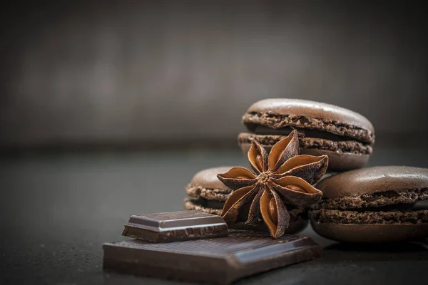 Chocolate ou café sabor francês macaroons e badiyan no fundo escuro — Fotografia de Stock