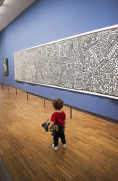 Baby sitting and see on picture on Keith Haring exhibition in Albertina gallery — Stock Photo, Image