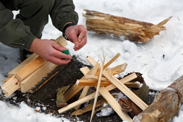 En man slår en match för att göra upp eld i skogen. — Stockfoto