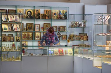 Ortodoks Dükkanı kilise içinde. Başörtüsü satış dini kap, mumlar ve simgeler tezgahın arkasındaki kadın. Rusya.