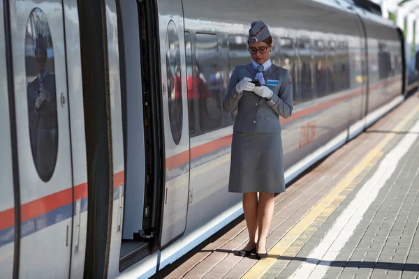 Toglederen venter på passagererne i det elektriske højhastighedstog Sapsan mellem Moskva og Sankt Petersborg. Moskva, Rusland - Stock-foto