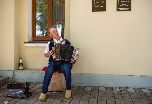 En ældre mand spiller den russiske harmonika foran registerkontoret. Suzdal, Rusland . - Stock-foto