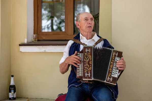 En ældre mand spiller den russiske harmonika foran registerkontoret. Suzdal, Rusland . - Stock-foto