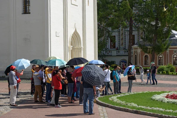 Группа азиатских туристов, прогуливающихся под зонтиками в Троицкой лавре Святого Сергия. Сергиев Посад, Золотое кольцо, Россия — стоковое фото