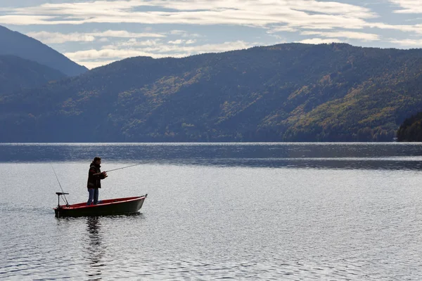 A lone fisherman in a motor boat on the lake Millstatt. Gurktal Alps, state of Carinthia, Austria Stock Picture