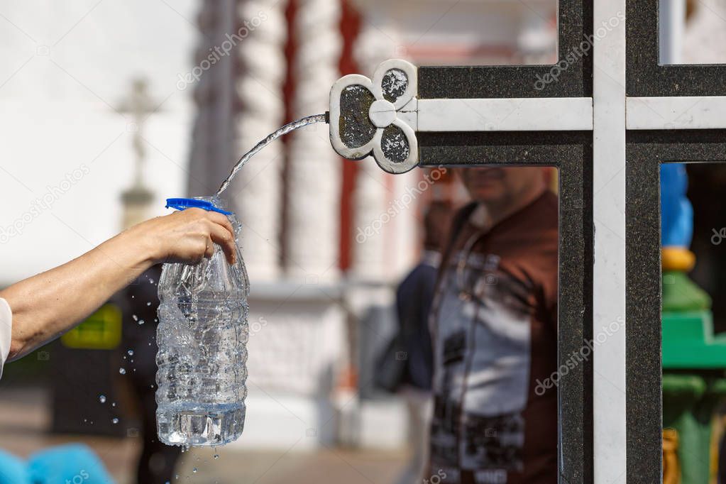 Pouring the holy water in a bottle from the Holy spring at the Sergiyev Posad monastery. Moscow region, Golden ring, Russia.