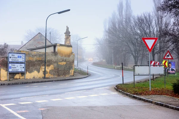 Vehículos que se mueven en una sinuosa carretera rural a través de la ciudad histórica en un día de niebla de invierno. Guntersdorf, Baja Austria . — Foto de Stock