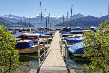 Güneşli bir bahar gününde, Weggis kasabası yakınlarındaki karlı Alplere bakan Lucerne Gölü 'ndeki tekne limanı. Lucerne Bölgesi İsviçre 'de Lucerne Kantonu' nda..