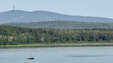 Motorlu tekne ile bir dağ nehir üzerinde gidiyor. Yer göktaşı düşme. Chebarkul Gölü. Dağ orman. Panorama. Gri gökyüzü. Küçük sis. Haze. Sonbaharda Ural Dağları.