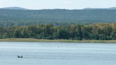 Motorlu tekne ile bir dağ nehir üzerinde gidiyor. Yer göktaşı düşme. Chebarkul Gölü. Dağ orman. Panorama. Gri gökyüzü. Küçük sis. Haze. Sonbaharda Ural Dağları.