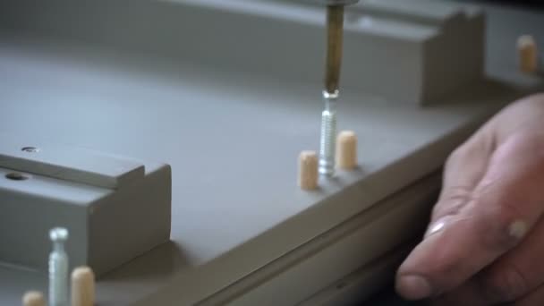 The worker screws the screw into the furniture shape with a screwdriver. Assembling furniture. — Stock Video