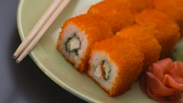 Sushi tekercs, a kaliforniai tekercs egy tányérra, pálcika, pácolt gyömbér és wasabi. Panoráma. — Stock videók