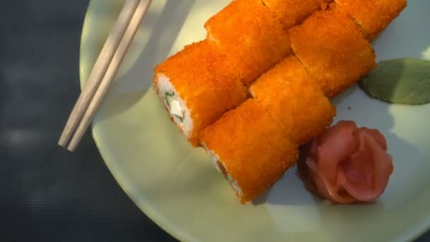 Rolo de sushi, rolos da Califórnia num prato com pauzinhos, gengibre marinado e wasabi. Feixe de luz . — Vídeo de Stock