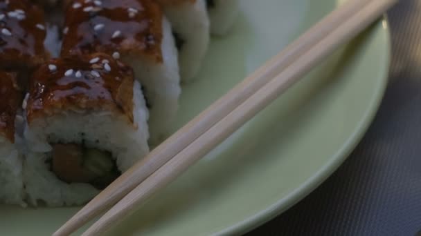 Incantevoli panini di sushi quadrati "Dragon" con anguilla, salmone, cetriolo, nori, riso sushi, sesamo. Piastra. Bacchette, zenzero marinato e wasabi. Primo piano . — Video Stock
