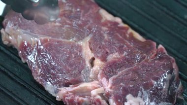 Sığır eti biftek ızgara Forseps ile kaldırdı ve diğer tarafa çevirdi. Ağır çekim.