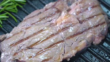 Sığır eti biftek ızgara Forseps ile kaldırdı ve diğer tarafa çevirdi. Ağır çekim.