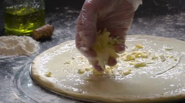 Pizza yemek. Taze rendelenmiş peynir pizza hamuru için ekleme eller. Pizza malzemeleri unlu ahşap masa üzerinde. Ağır çekim.