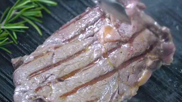 Rindersteak auf dem Grill wird mit einer Pinzette angehoben und auf die andere Seite gedreht. Zeitlupe. — Stockvideo