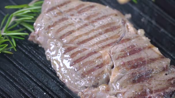 Le steak de boeuf sur le gril est saupoudré de sel. Mouvement lent . — Video