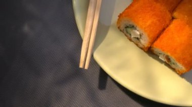 Suşi roll, bir tabak yemek çubukları, Marine zencefil ve wasabi ile Kaliforniya rulo. Yakın çekim. Işık demeti.