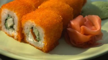 Suşi roll, bir tabak yemek çubukları, Marine zencefil ve wasabi ile Kaliforniya rulo. Yakın çekim. Işık demeti.