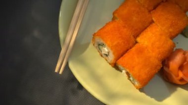 Suşi roll, bir tabak yemek çubukları, Marine zencefil ve wasabi ile Kaliforniya rulo. Işık demeti.