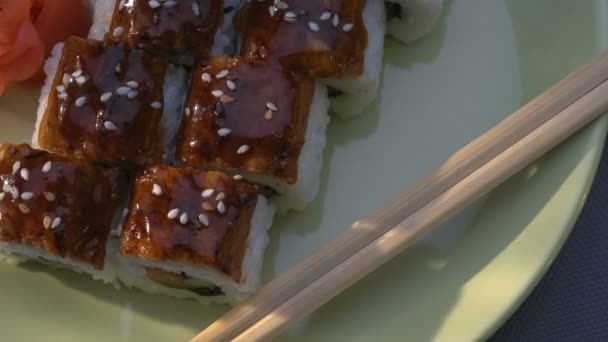 Aptitretande fantastiska "Dragon" fyrkantig sushi rullar med ål, lax, gurka, nori, sushiris, sesam. Plattan. Ätpinnar, marinerad ingefära och wasabi. Närbild. — Stockvideo