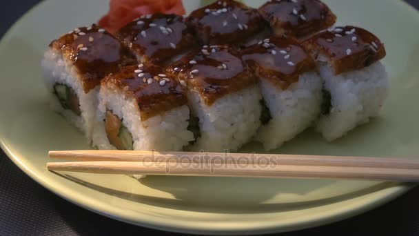 Chutný úžasné "Dragon" čtvercové sushi rohlíky s úhoř, losos, okurka, nori, sushi rýže, sezam. Deska. Hůlky, marinovaným zázvorem a wasabi. Detail. — Stock video